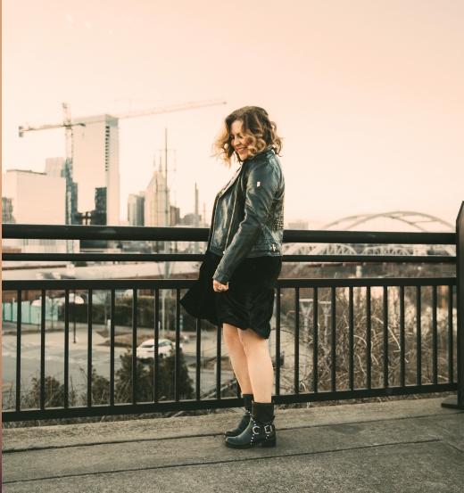 A woman standing on the side of a bridge.